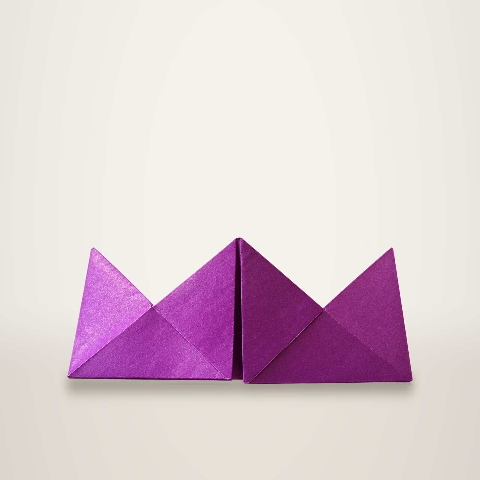 Deux modules d'origami en papier violet plié en triangles, posés côte à côte sur un fond blanc uni.